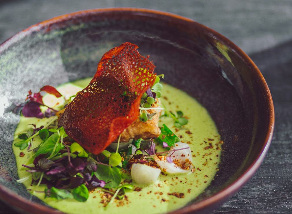 Plated dish with green sauce in a dark bowl