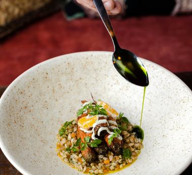 Chef spooning sauce over a plated dish