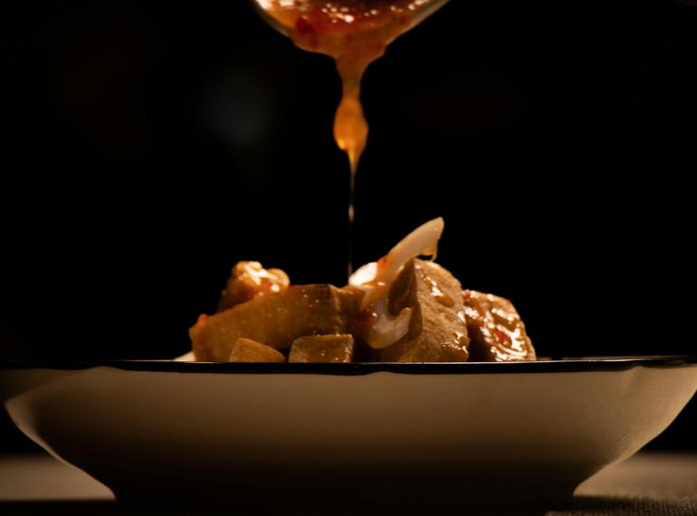 Sauce being drizzled over a dish in low light